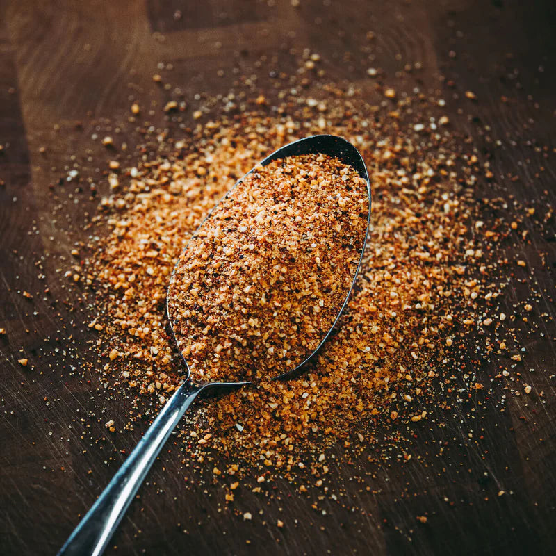 Spoonful of brown spice mix on a wooden surface